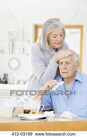 Stock Photo - Older woman feeling sick husband's forehead. Fotosearch