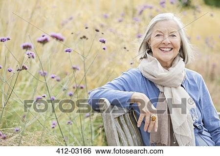 Older woman sitting on park bench View Large Photo Image Stock Photograph - Older woman sitting on park bench. Fotosearch
