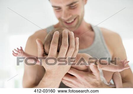 Stock Image - Smiling father holding newborn baby. Fotosearch