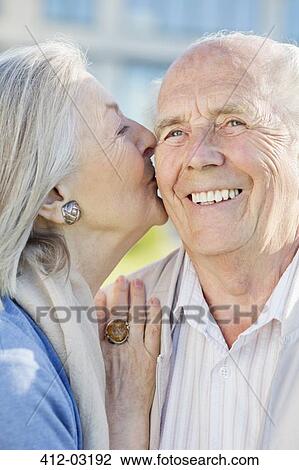 Stock Image - Smiling older couple kissing outdoors. Fotosearch