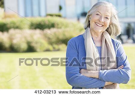 Stock Image - Smiling older woman standing outdoors. Fotosearch
