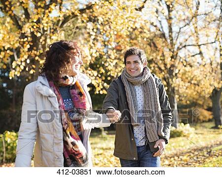 Stock Image - Couple holding hands in park. Fotosearch