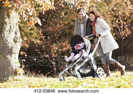 Stock Photograph - Couple pushing baby in stroller in park. Fotosearch