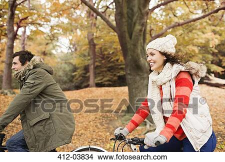 Couple riding bicycles in park View Large Photo Image Picture - Couple riding bicycles in park. Fotosearch