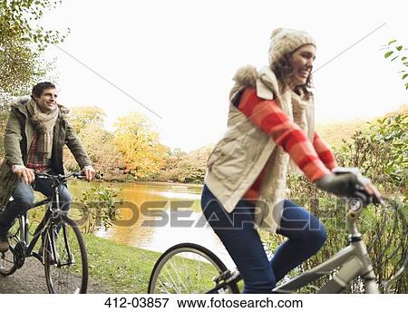 Stock Photo - Couple riding bicycles in park. Fotosearch
