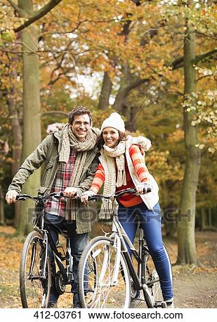 Couple riding bicycles together in park View Large Photo Image Stock Image - Couple riding bicycles together in park. Fotosearch