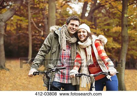 Couple riding bicycles together in park View Large Photo Image Stock Photo - Couple riding bicycles together in park. Fotosearch