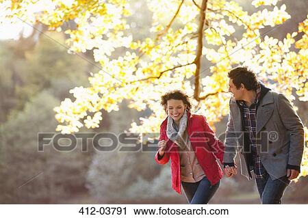 Stock Image - Couple walking together in park. Fotosearch