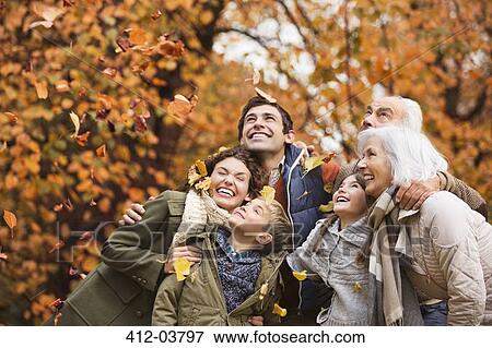 Stock Photo - Family playing in autumn leaves in park. Fotosearch