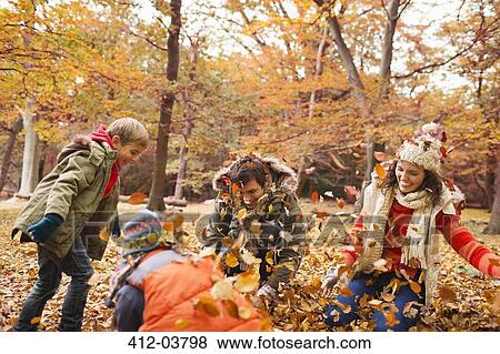 Family playing in autumn leaves in park View Large Photo Image Stock Photo - Family playing in autumn leaves in park. Fotosearch