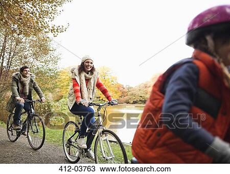 Family riding bicycles together in park View Large Photo Image Stock Image - Family riding bicycles together in park. Fotosearch