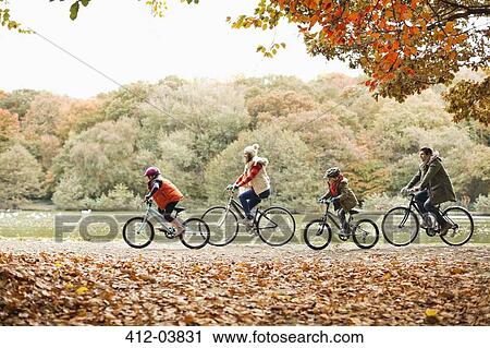 Stock Image - Family riding bicycles together in park. Fotosearch