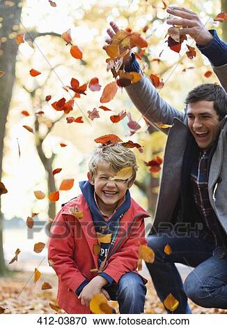 Stock Image - Father and son playing in autumn leaves. Fotosearch