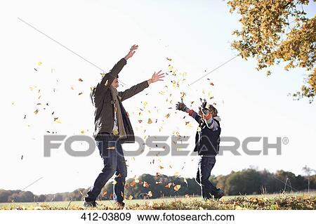 Stock Photo - Father and son playing in autumn leaves. Fotosearch