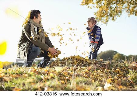 Stock Photograph - Father and son playing in autumn leaves. Fotosearch
