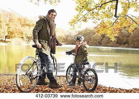 Father and son sitting on bicycles in park View Large Photo Image Stock Photo - Father and son sitting on bicycles in park. Fotosearch