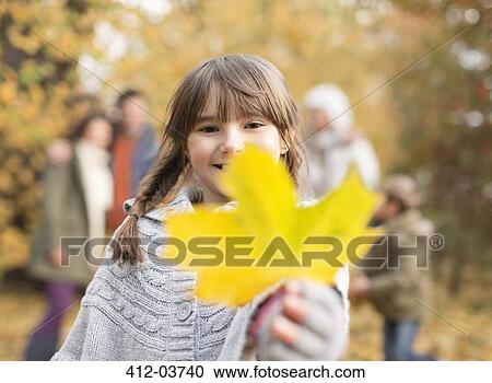 Girl holding autumn leaf in park View Large Photo Image Stock Image - Girl holding autumn leaf in park. Fotosearch