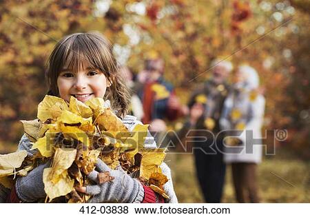 Stock Photo - Girl playing with autumn leaves in park. Fotosearch