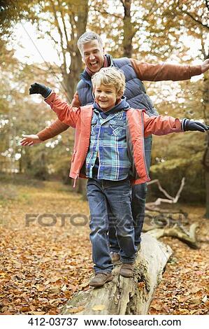 Man and grandson playing on log in park View Large Photo Image Stock Photo - Man and grandson playing on log in park. Fotosearch