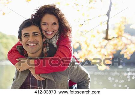 Man carrying girlfriend piggyback in park View Large Photo Image Stock Image - Man carrying girlfriend piggyback in park. Fotosearch