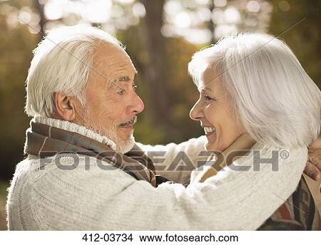 Picture - Older couple hugging outdoors. Fotosearch