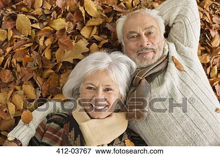 Older couple laying in autumn leaves View Large Photo Image Stock Photo - Older couple laying in autumn leaves. Fotosearch