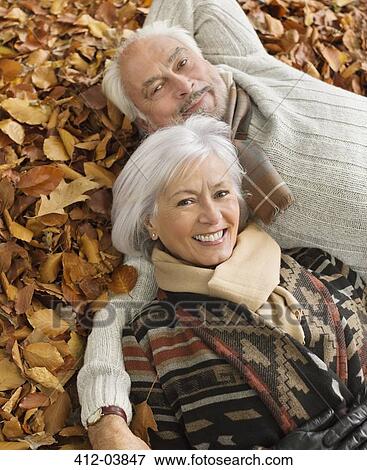 Stock Photo - Older couple laying in autumn leaves. Fotosearch
