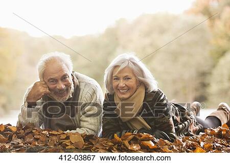 Older couple laying in autumn leaves View Large Photo Image Stock Photo - Older couple laying in autumn leaves. Fotosearch