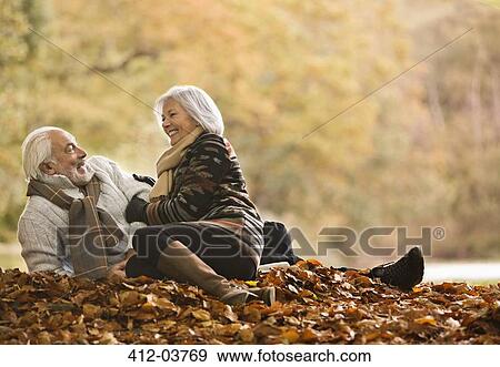 Older couple sitting in autumn leaves View Large Photo Image Stock Photo - Older couple sitting in autumn leaves. Fotosearch