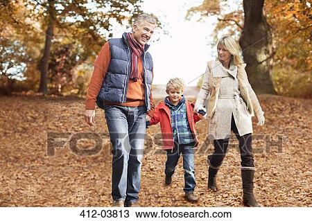 Stock Image - Older couple walking with grandson in park. Fotosearch