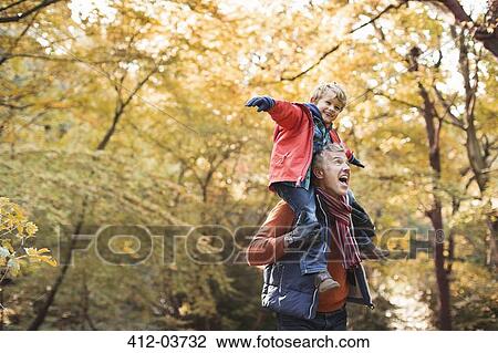 Stock Image - Older man carrying grandson on shoulders. Fotosearch