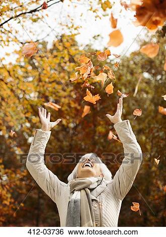 Older woman playing in autumn leaves View Large Photo Image Stock Photograph - Older woman playing in autumn leaves. Fotosearch