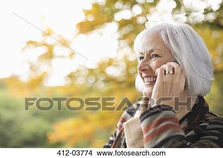 Older woman talking on cell phone in park View Large Photo Image Picture - Older woman talking on cell phone in park. Fotosearch