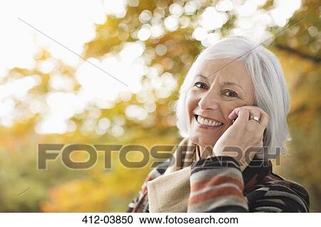 Older woman talking on cell phone in park View Large Photo Image Stock Image - Older woman talking on cell phone in park. Fotosearch
