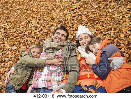 Smiling family laying in autumn leaves View Large Photo Image Stock Photo - Smiling family laying in autumn leaves. Fotosearch