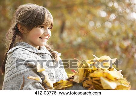 Smiling girl playing in autumn leaves View Large Photo Image Stock Photograph - Smiling girl playing in autumn leaves. Fotosearch
