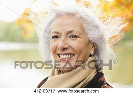 Stock Photo - Smiling older woman standing in park. Fotosearch