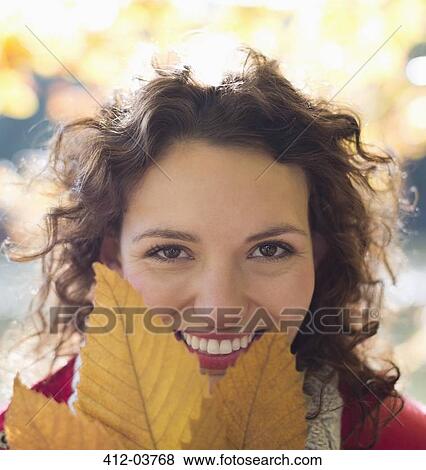 Smiling woman holding autumn leaf View Large Photo Image Stock Photo - Smiling woman holding autumn leaf. Fotosearch