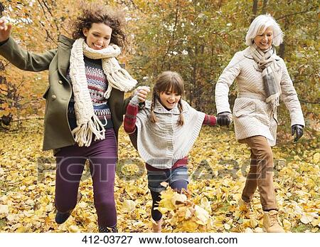 Stock Photo - Three generations of women playing in autumn leaves. Fotosearch