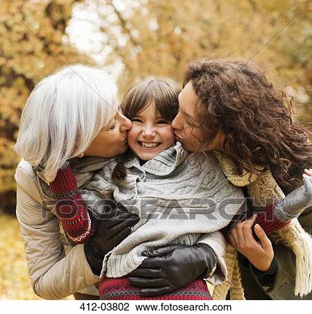 Woman and daughter kissing girl in park View Large Photo Image Stock Image - Woman and daughter kissing girl in park. Fotosearch