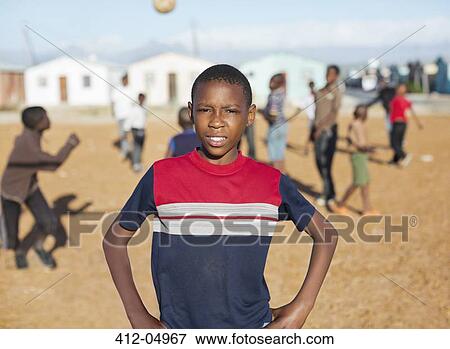 Stock Photo - Boy standing in dirt field. Fotosearch