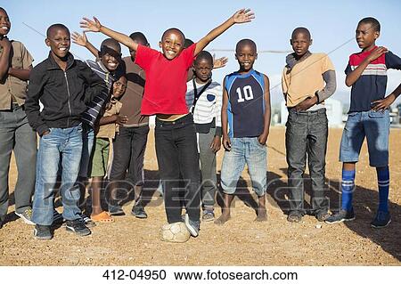 Stock Image - Boys cheering together in dirt field. Fotosearch