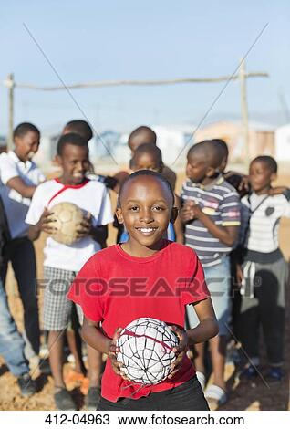 Boys holding soccer balls in dirt field View Large Photo Image Stock Image - Boys holding soccer balls in dirt field. Fotosearch