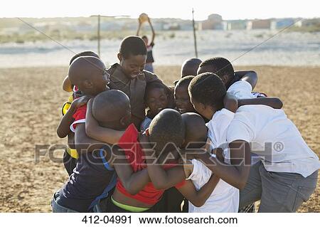 Boys huddled together in dirt field View Large Photo Image Stock Image - Boys huddled together in dirt field. Fotosearch