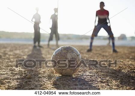 Boys playing soccer together in dirt field View Large Photo Image Picture - Boys playing soccer together in dirt field. Fotosearch