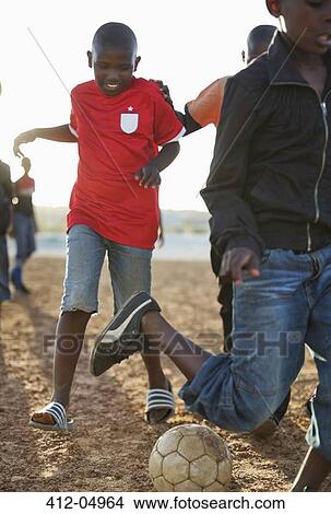 Boys playing soccer together in dirt field View Large Photo Image Picture - Boys playing soccer together in dirt field. Fotosearch