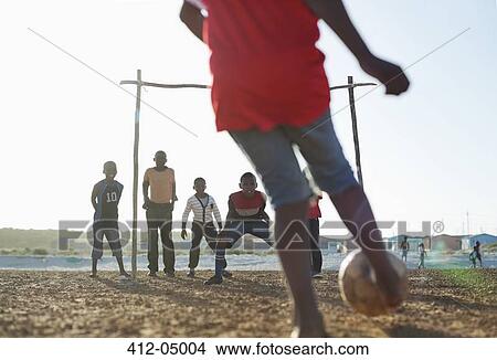 Boys playing soccer together in dirt field View Large Photo Image Picture - Boys playing soccer together in dirt field. Fotosearch