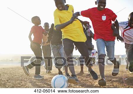 Boys playing soccer together in dirt field View Large Photo Image Picture - Boys playing soccer together in dirt field. Fotosearch