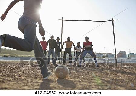 Boys playing soccer together in dirt field View Large Photo Image Stock Image - Boys playing soccer together in dirt field. Fotosearch