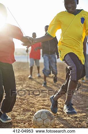 Boys playing soccer together in dirt field View Large Photo Image Stock Image - Boys playing soccer together in dirt field. Fotosearch